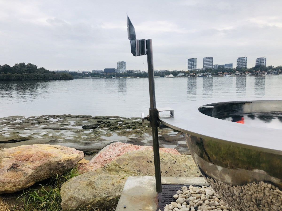 A stainless spit bracket fitted to the edge of a stainless Teppanyaki top plate, beside a river